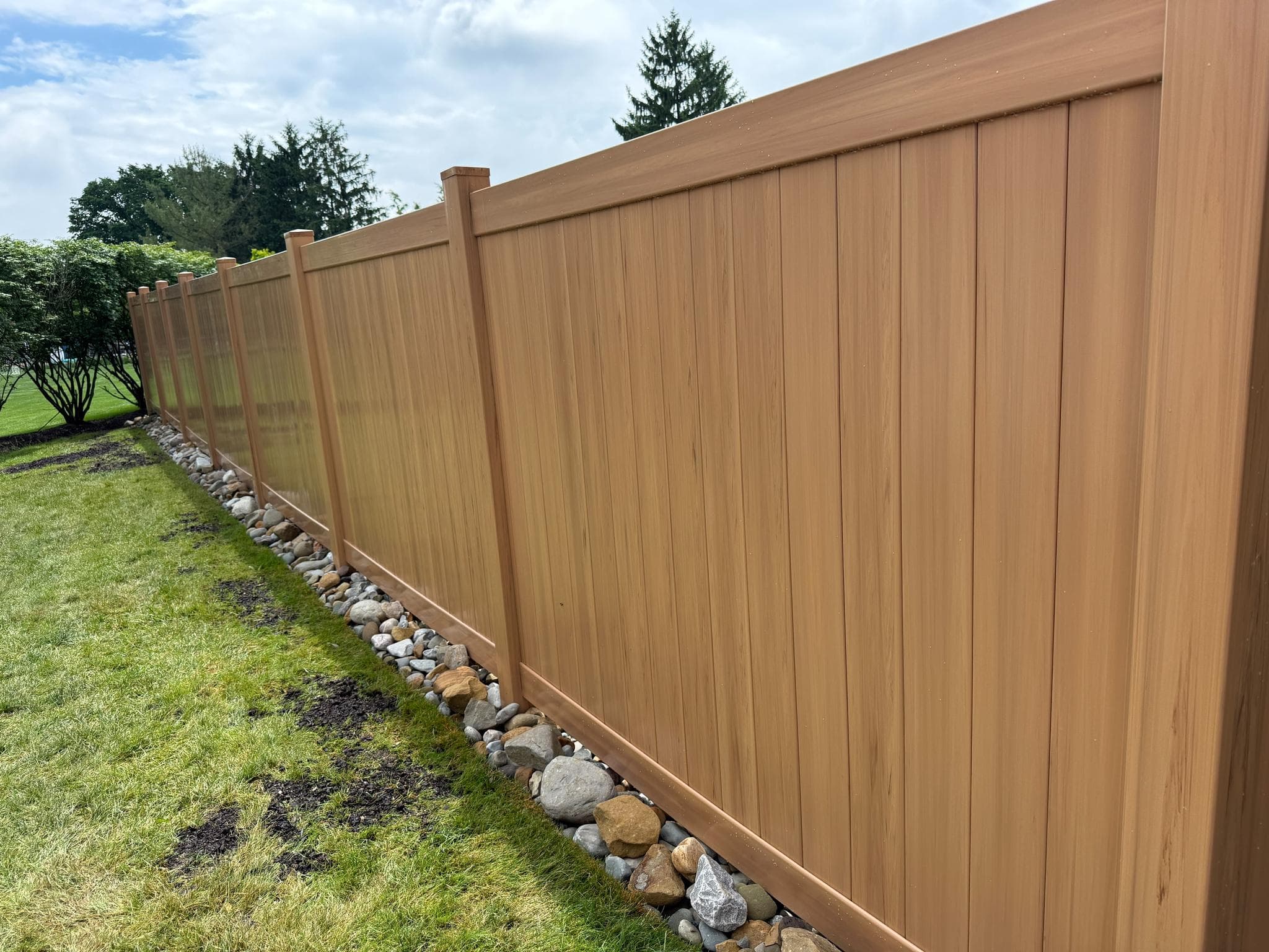Wood-grain vinyl privacy fence installed along a Pittsburgh property line